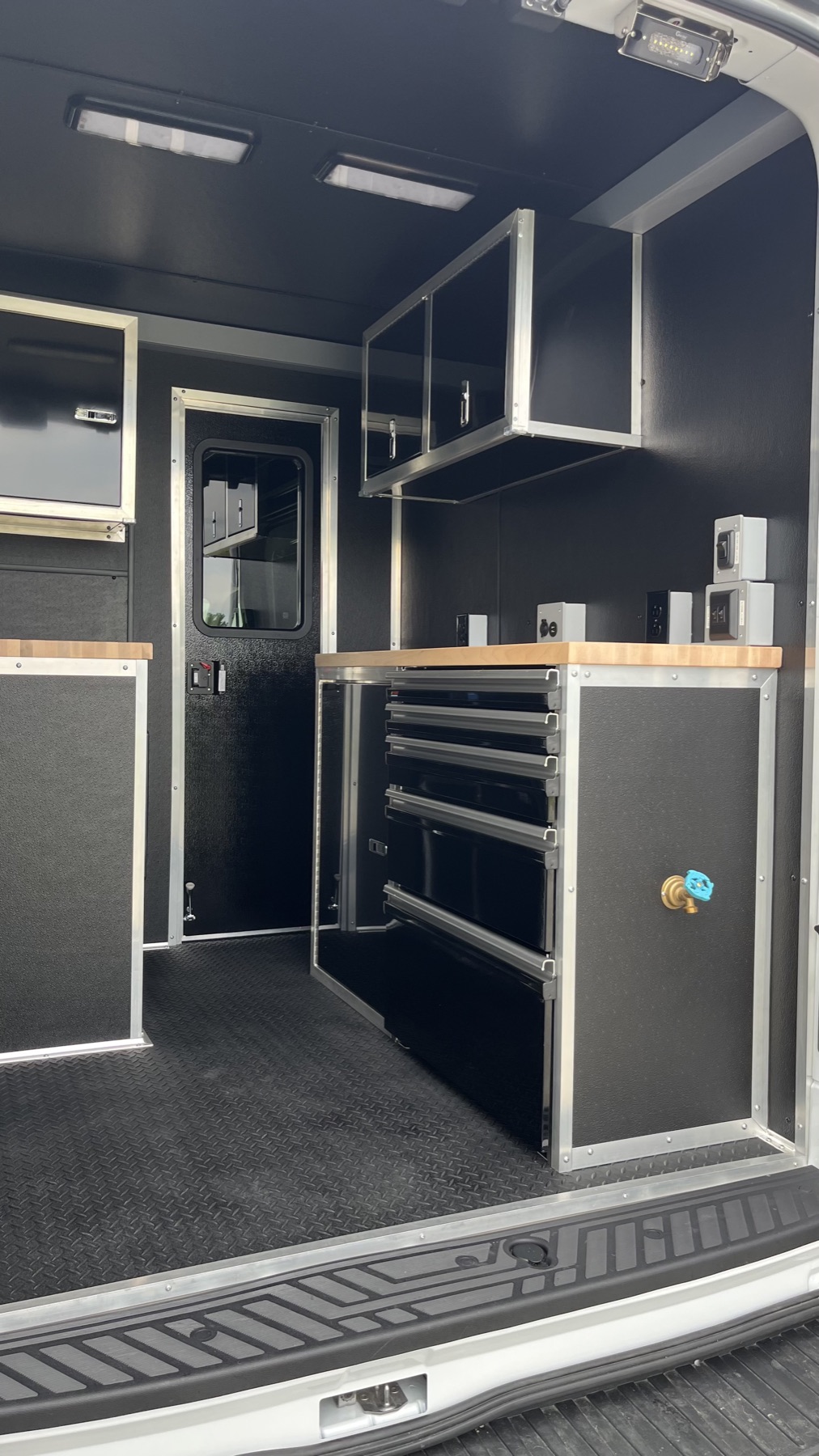 Blacked-out interior cabinetry with upper storage cabinets and wood countertop