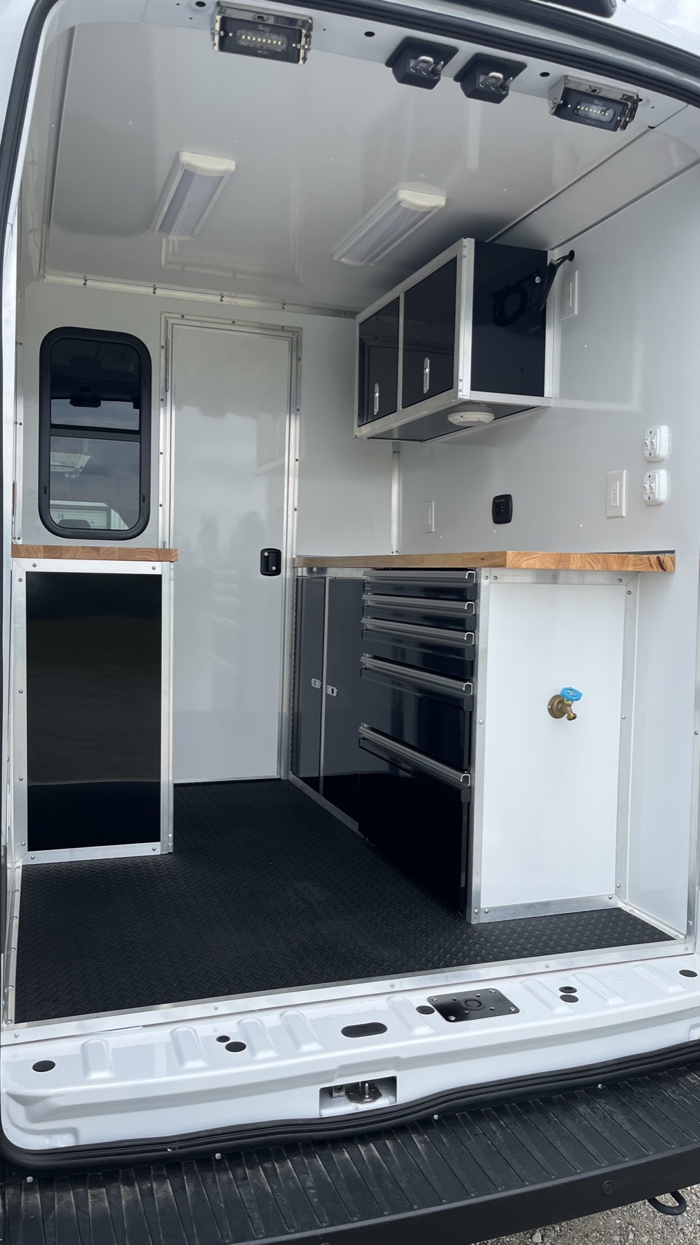 Interior view of white cabinetry, tool drawers, and plumbed water fixture