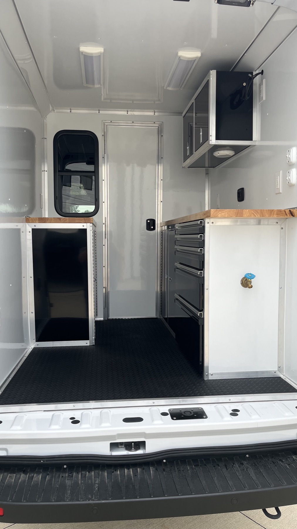 White aluminum cabinetry with tool drawers and butcher-block countertop inside a work van
