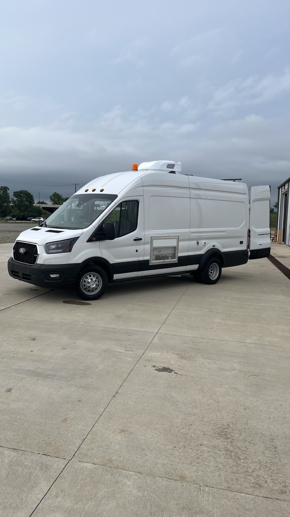Side profile of converted Ford Transit high-roof van with side service door open