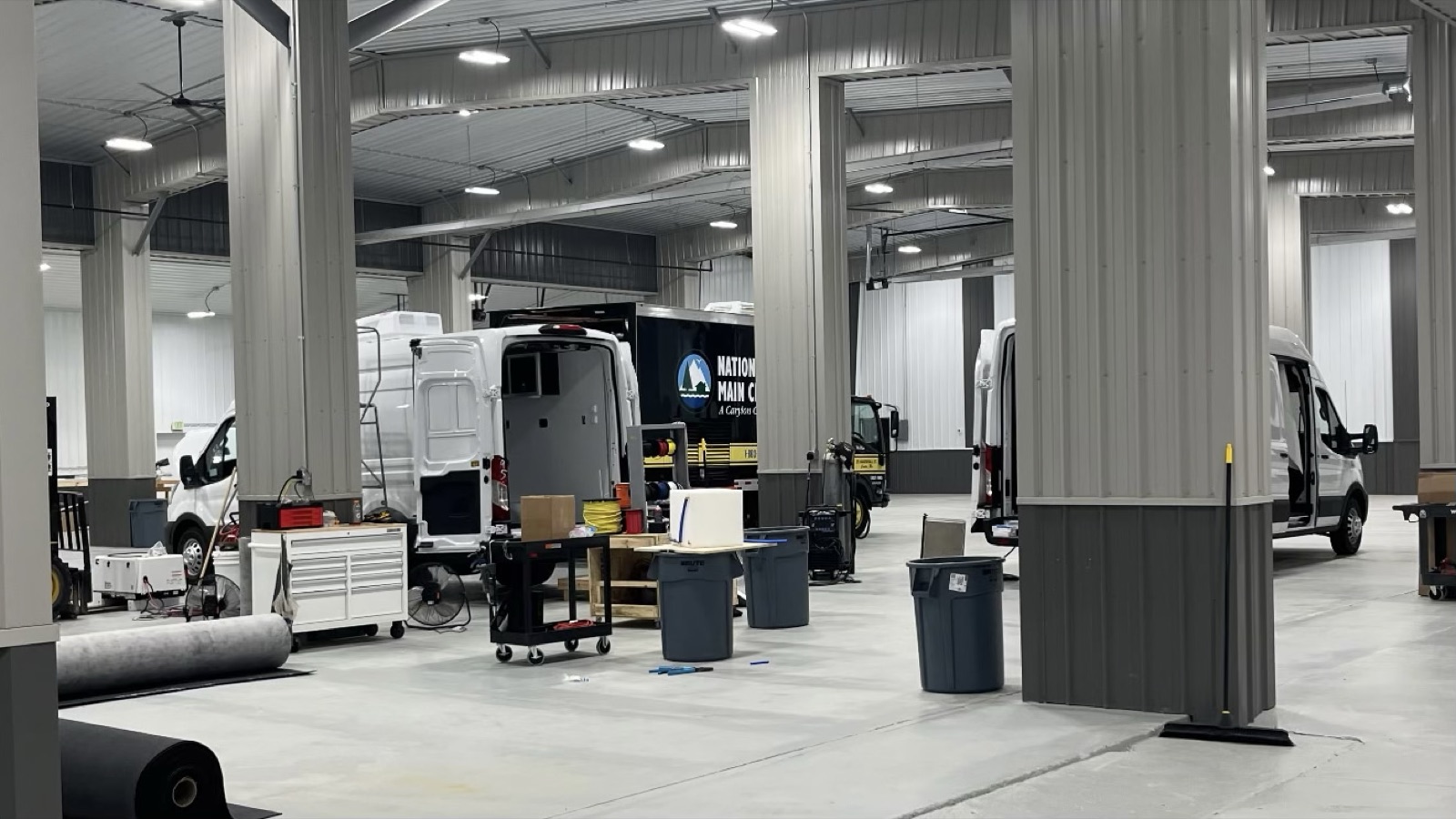 Vans and a box truck mid-build on the shop floor at V Tech Conversions