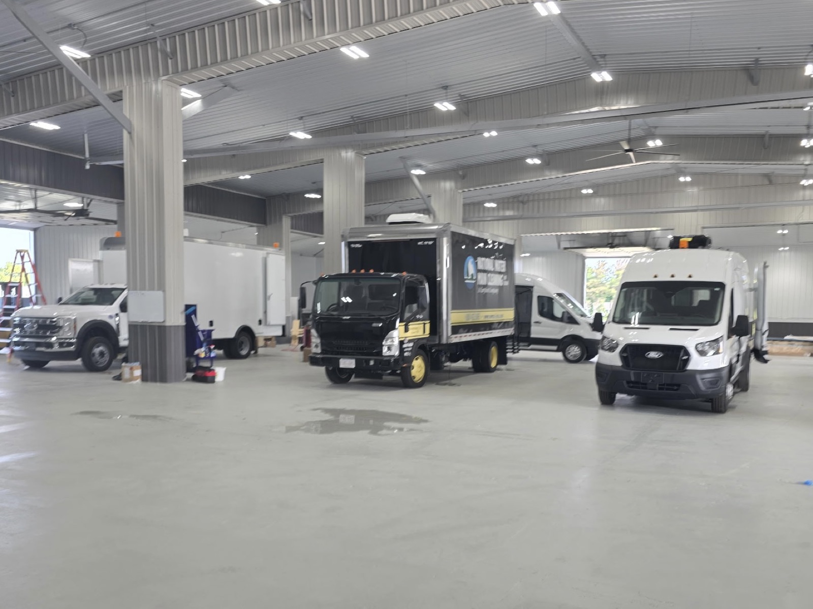 Wide view of the V Tech Conversions facility with multiple vans and trucks in for upfitting